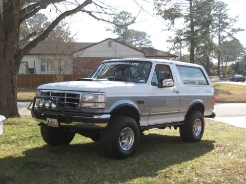 1994 Ford Bronco - This two-tone Ford Bronco is parked on a grassy area in front of a house.