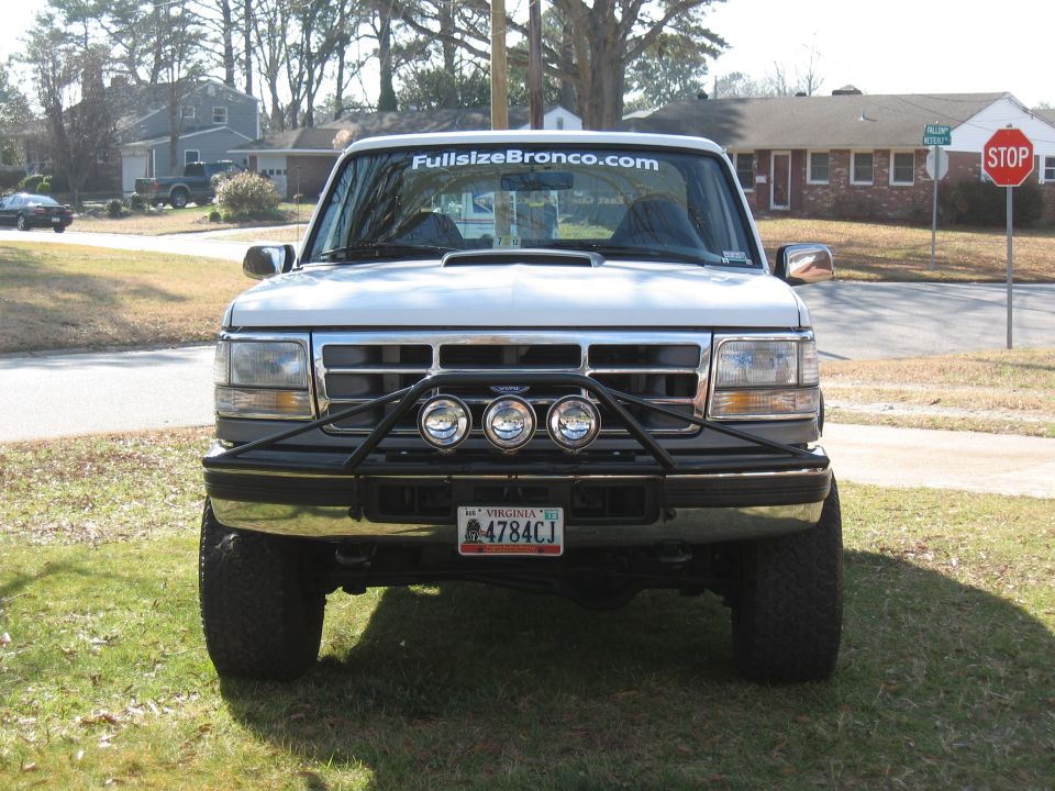 White Ford Bronco with aftermarket grille guard and lights. Front view
