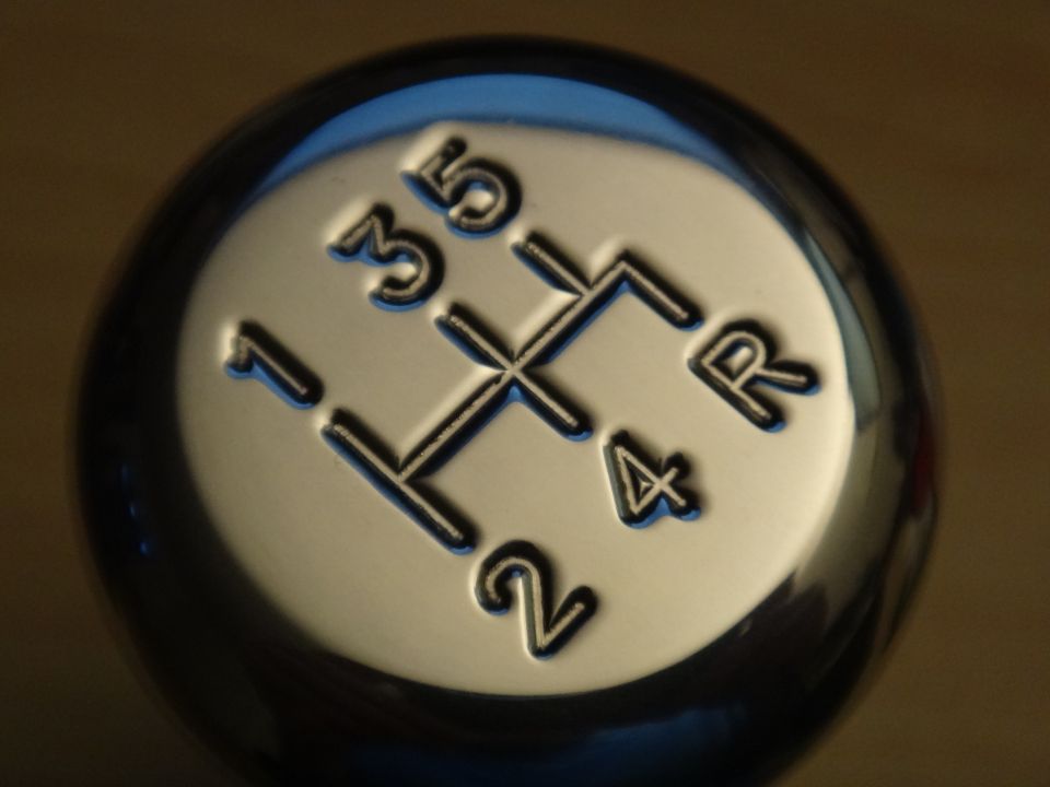 Close-up of a 5-speed manual transmission shift knob with gears labeled 1, 2, 3, 4, 5, and R
