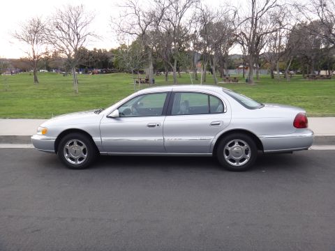 2000 Lincoln Continental - Side view of a silver 2000 Lincoln Continental parked on a street with a park in the background.