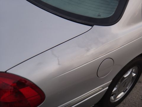 2000 Lincoln Continental - The rear quarter panel of a silver sedan is visible, including the fuel door and a portion of the taillight.