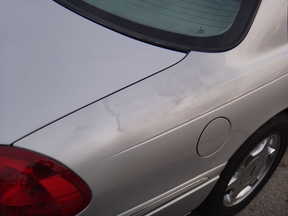 Silver sedan's rear quarter panel showing a fuel door and part of a taillight