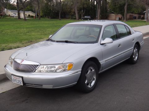 2000 Lincoln Continental - A silver sedan is parked on the side of a street in a suburban neighborhood.