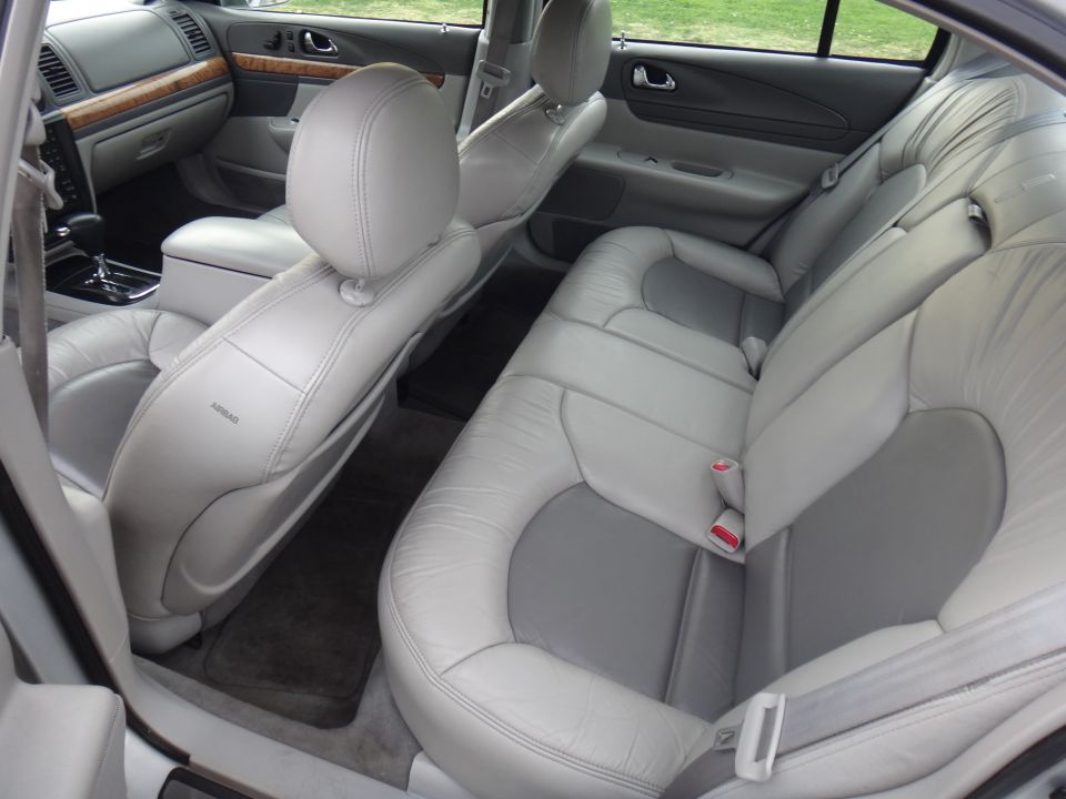 Interior view of a car's back seats and front passenger seat. Shows light gray leather seats with darker gray inserts