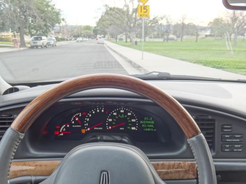 2000 Lincoln Continental - The dashboard displays average mileage and trip information while driving down a suburban street.