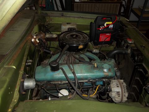1971 Dodge Dart - The engine bay of a 1971 Dodge Dart, a jump starter connected to the battery.