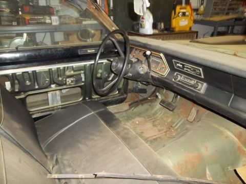 1971 Dodge Dart - The interior of a 1971 Dodge Dart shows its dashboard, steering wheel, and seats, with visible rust on the floor.