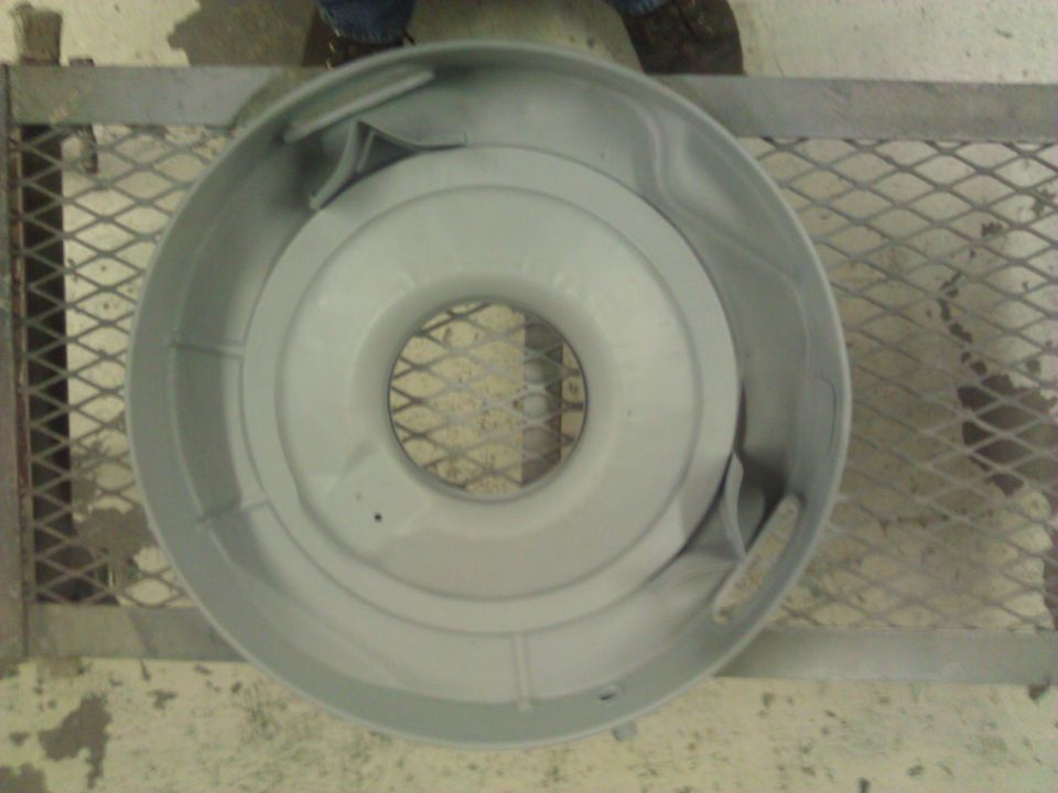 Gray air cleaner housing with a circular opening in the center, sitting on a metal grate