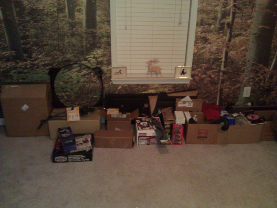 Boxes and car parts piled in front of a forest-themed wallpaper