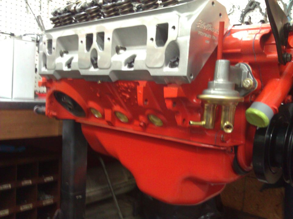 Close-up of a red engine block with a silver cylinder head and a fuel pump attached