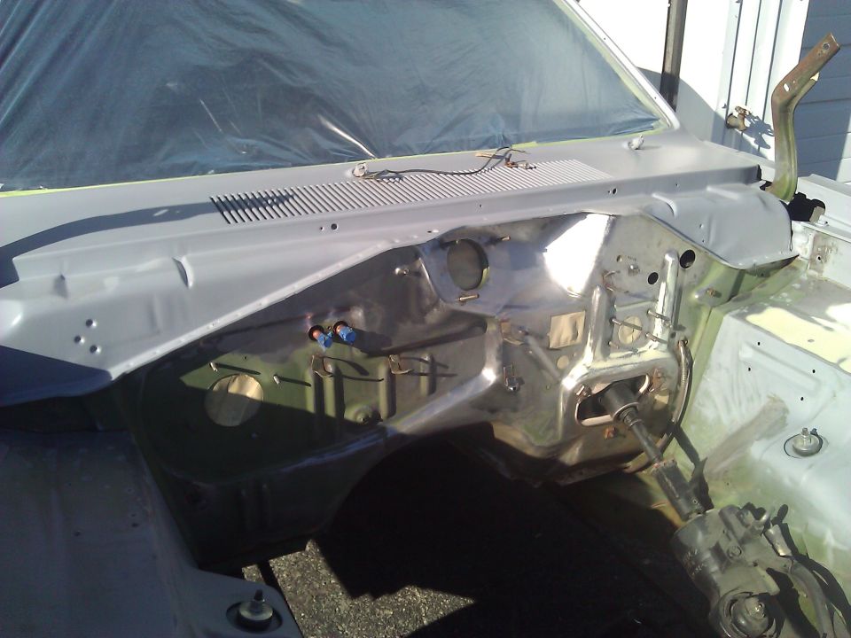 Car firewall area, looks like it's being prepped for paint. Windshield covered in plastic