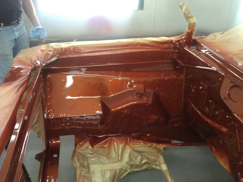 Car interior being painted brown, with masking tape and plastic sheeting
