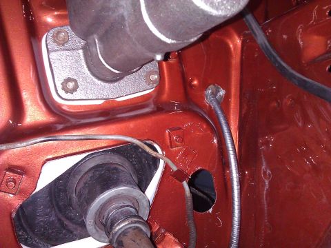 1971 Dodge Dart - Close-up view of the engine bay firewall, painted orange, showing components like the brake master cylinder and the opening for the steerin…