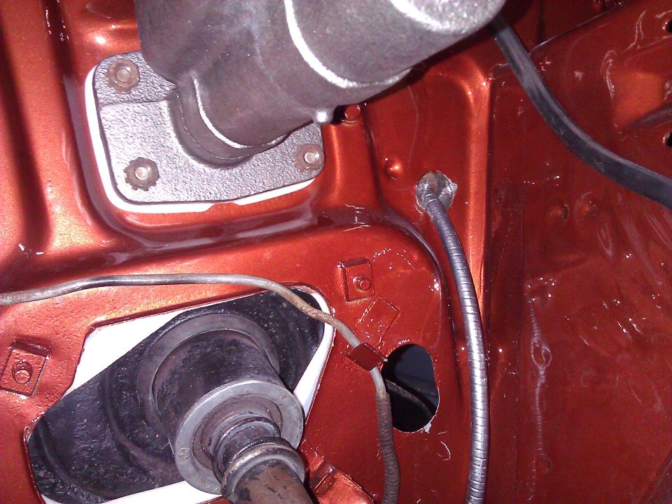 Orange painted engine bay firewall with brake master cylinder and steering column opening