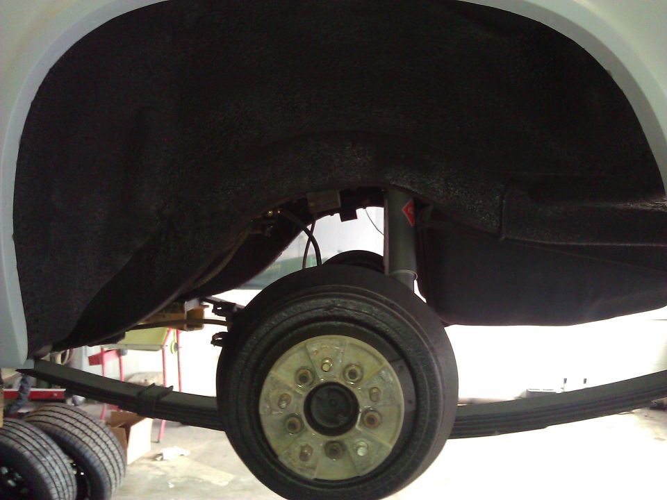 Rear wheel well interior with leaf spring suspension and drum brake assembly visible