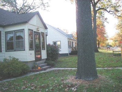 1997 Ford Taurus - A residential street scene with houses and a large tree in the foreground during autumn.