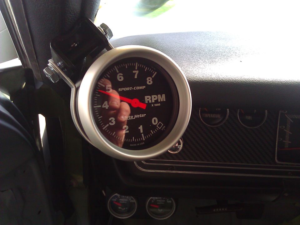 Tachometer and dashboard gauges in a car interior, with a red needle pointing to 4.5