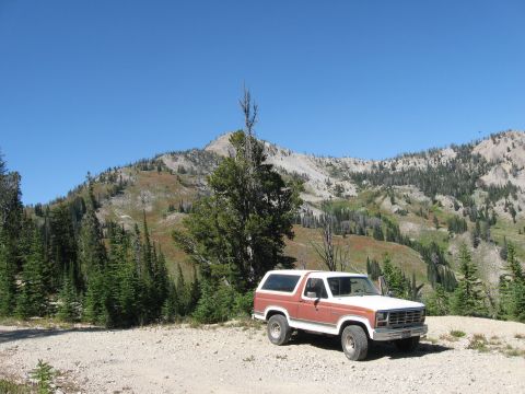 1981 Ford Bronco - A red and white Ford Bronco is parked in a scenic outdoor location with mountains and trees.