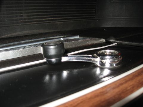 1968 Shelby GT500 - Close-up of a car's interior window crank handle with wood trim visible.