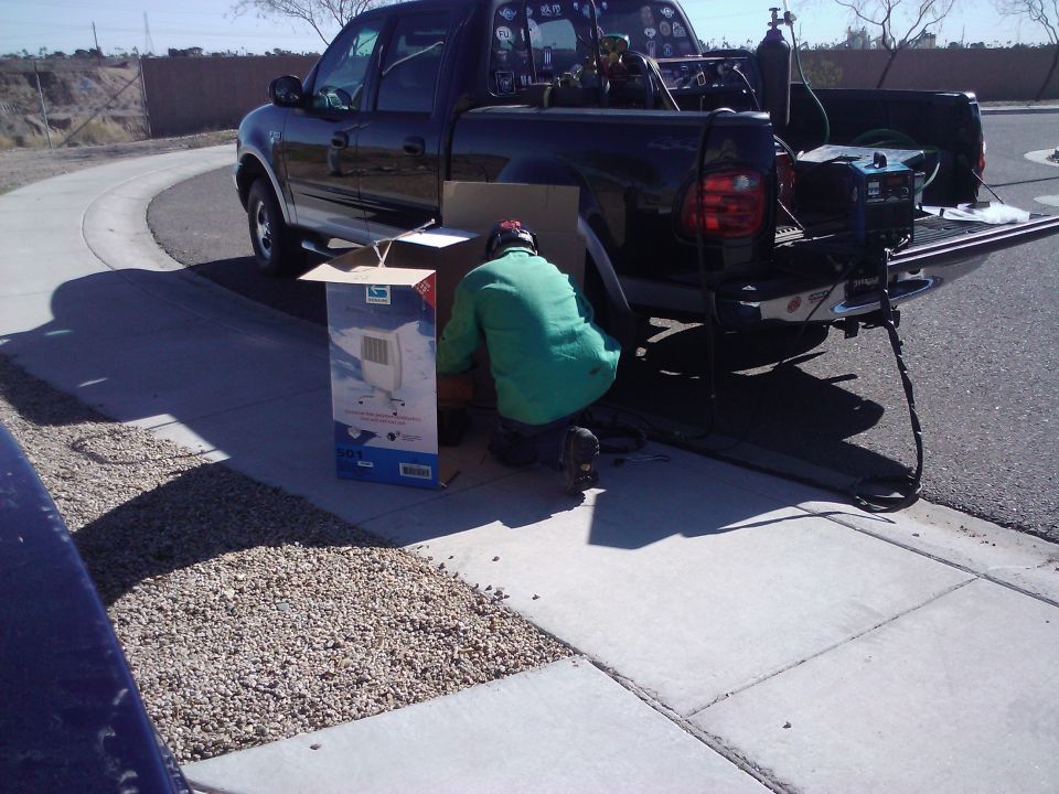 Black pickup truck rear view with welding equipment and a person working