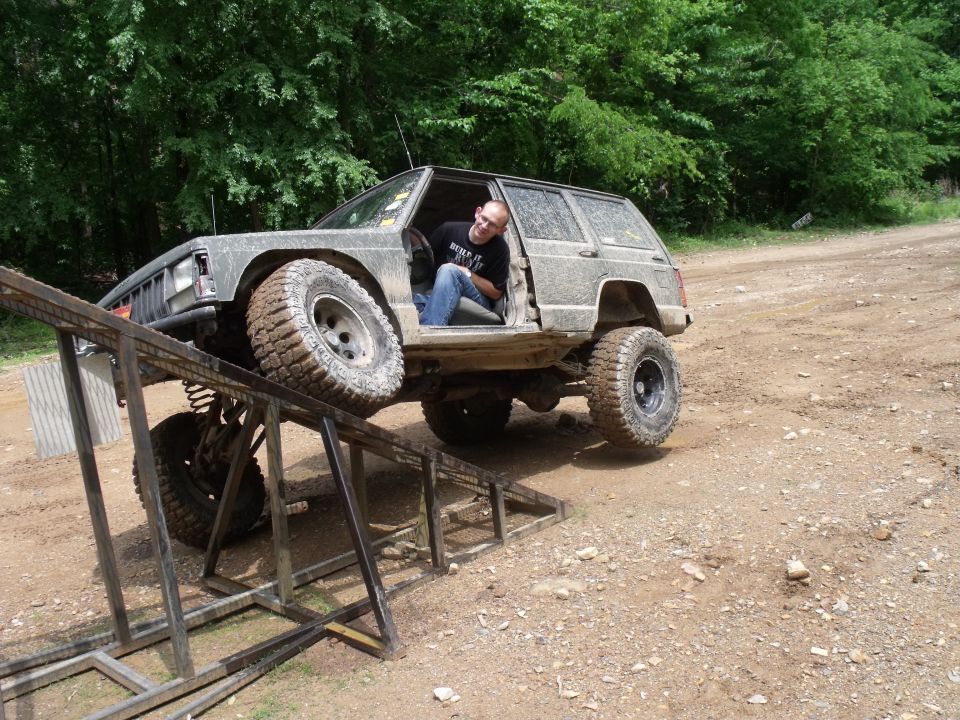 Modified 1992 Jeep Cherokee climbing a metal ramp, driver visible in open door
