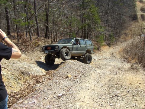 1992 Jeep Cherokee - A modified Jeep Cherokee navigates a challenging off-road trail with steep inclines and loose gravel.