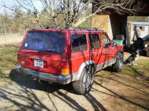 1992 Jeep Cherokee - A red Jeep Cherokee is parked in a yard with a dog sitting to the side.
