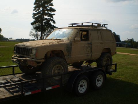 1992 Jeep Cherokee - A muddy Jeep Cherokee is loaded onto a trailer, ready for off-road adventures.