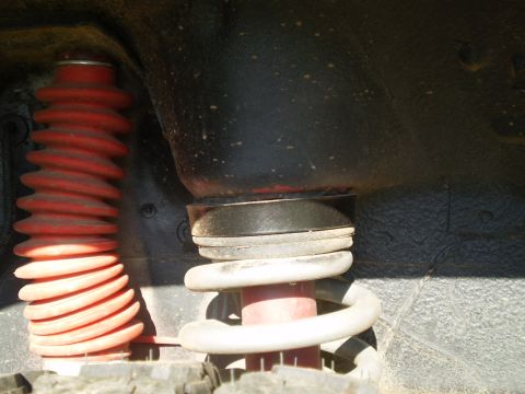 1992 Jeep Cherokee - Close-up view of the vehicle's suspension system, showing a red shock boot and a white coil spring.