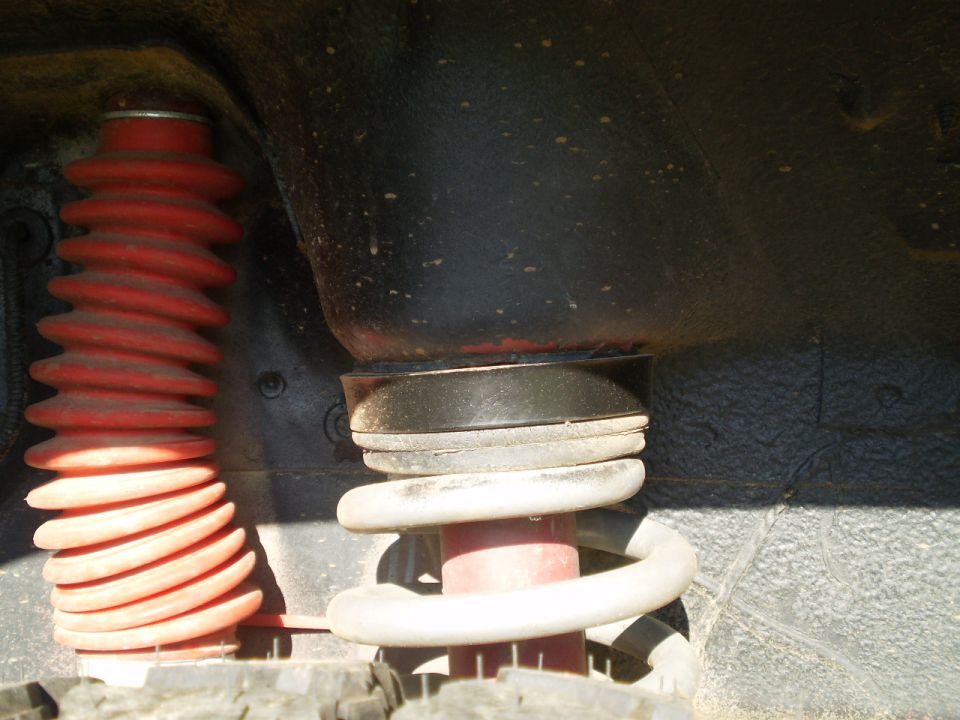 Red shock boot and white coil spring on a vehicle's suspension