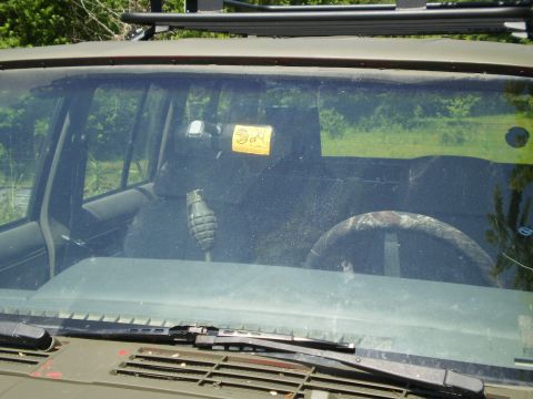 1992 Jeep Cherokee - Interior view of a 1992 Jeep Cherokee, a grenade on the dashboard and a yellow sticker on the windshield.
