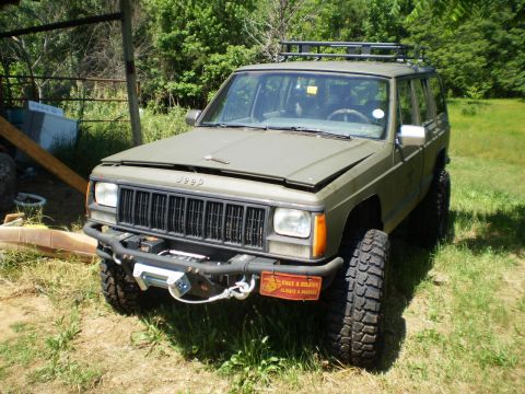 1992 Jeep Cherokee - Olive drab Jeep Cherokee with aftermarket bumper and winch, lifted suspension, and roof rack.