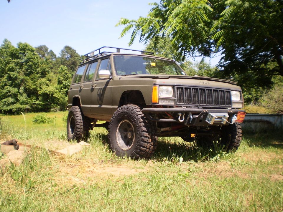 1992 Jeep Cherokee modified for off-roading, parked in grassy area with trees
