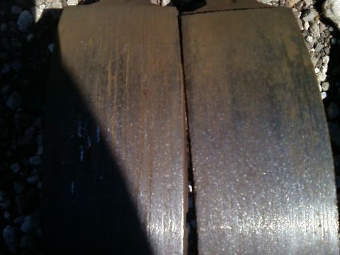 1988 Ford F-150 - Close-up view of two heavily used brake pads, showing signs of wear and corrosion.