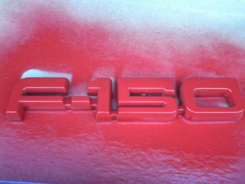1988 Ford F-150 - Close-up of a red F-150 emblem, possibly being painted.