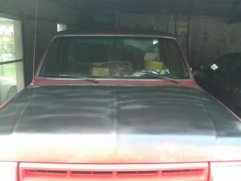 1988 Ford F-150 - A red pickup truck is parked inside a garage, with another vehicle visible to its side.