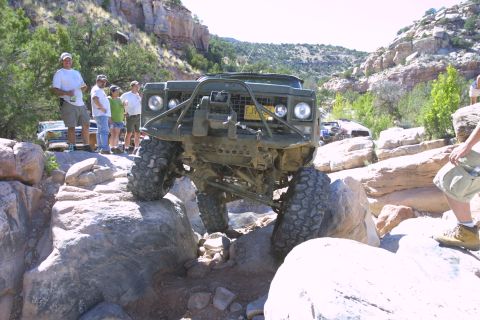 1979 Ford Bronco - Modified off-road vehicle tackling a rocky trail with spectators watching.