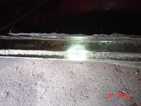 1988 Ford F-150 - A close-up view of the underside of a vehicle, showing rust and debris on the ground.