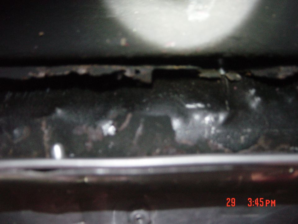 Close-up of rusted vehicle frame underside with some debris