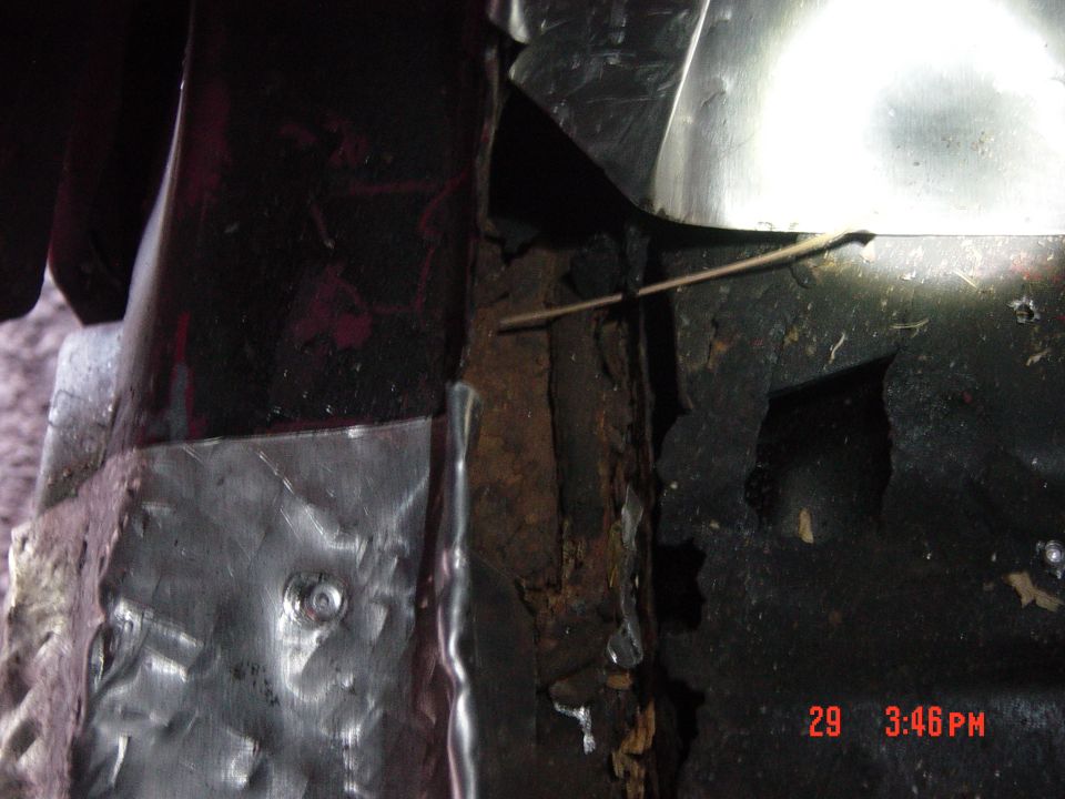 Close-up of rusted metal and a crudely applied patch panel on a vehicle's undercarriage