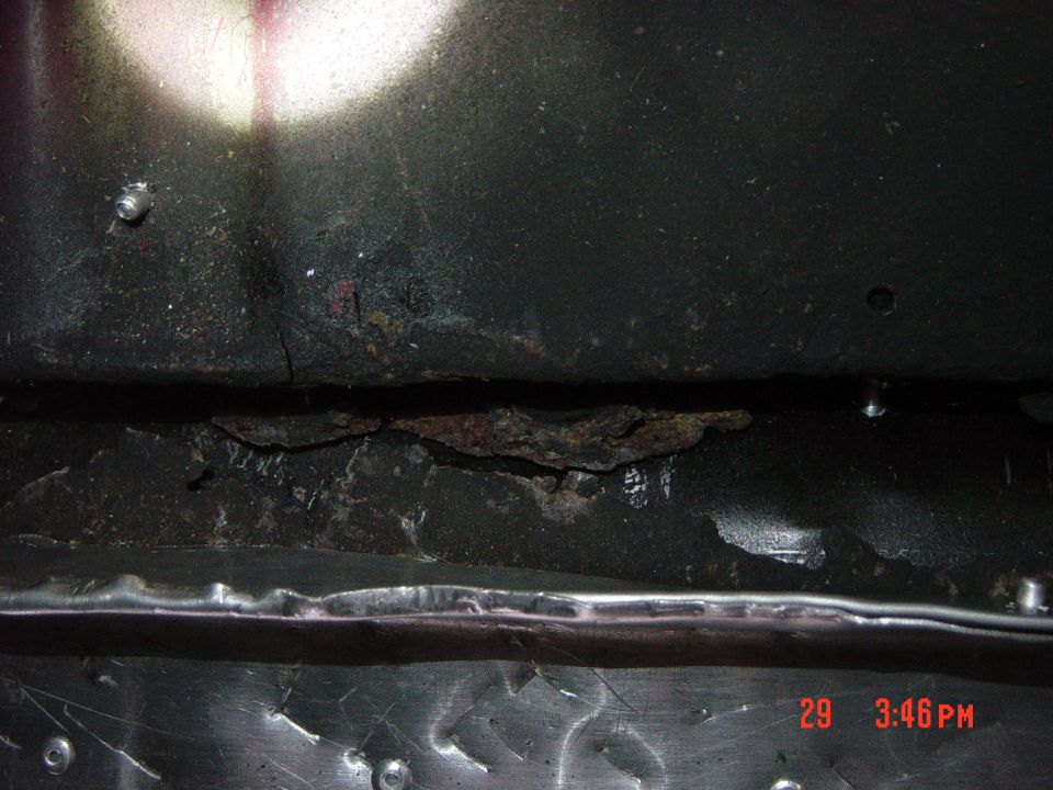 Close-up of a heavily rusted and damaged vehicle frame section