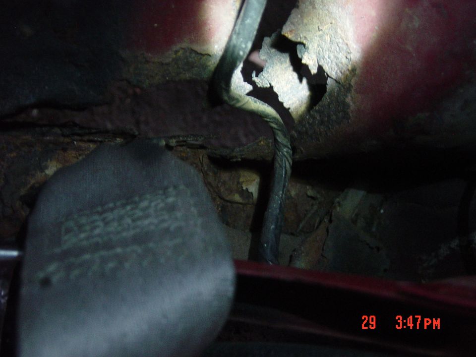 Seatbelt buckle and rusted metal under a vehicle