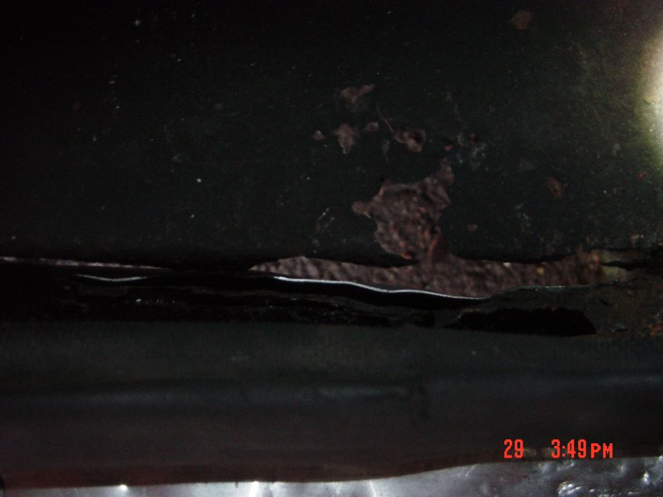 Close-up of rust and damage on a dark-colored vehicle panel