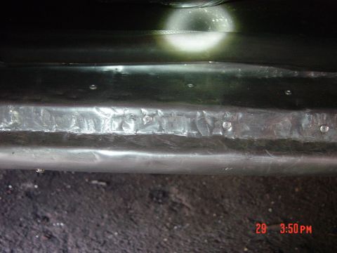 1988 Ford F-150 - Close-up of a dented metal bumper with a bright light illuminating the surface.