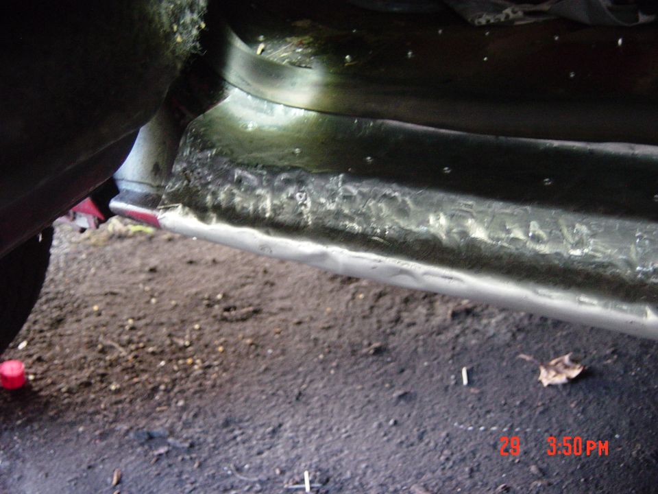Close-up of rusted metal on a vehicle's rocker panel, showing repair work