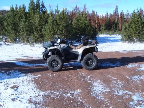 1994 Jeep Cherokee - An all-terrain vehicle sits on a dirt path surrounded by snow and pine trees under a clear blue sky.