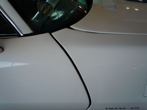 1982 Chevrolet Camaro - A detail shot of a white car's body panel seam, with a sticker visible on the windshield.