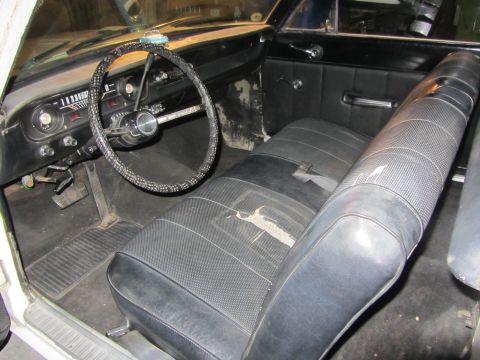 1964 Ford Ranchero - The interior of the vehicle shows signs of wear, including a torn driver's seat and a dated dashboard.