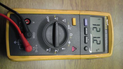 1989 Ford Bronco - A yellow Fluke multimeter shows a reading of 12.12 volts AC, with attached red and black test leads.
