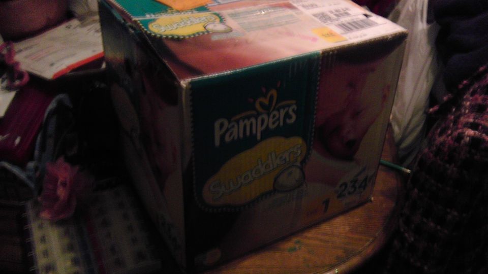 Box of Pampers Swaddlers diapers on a wooden table